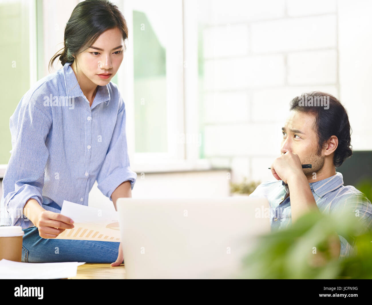 two asian business coworkers working together in office using laptop computer with serious expression on face. Stock Photo