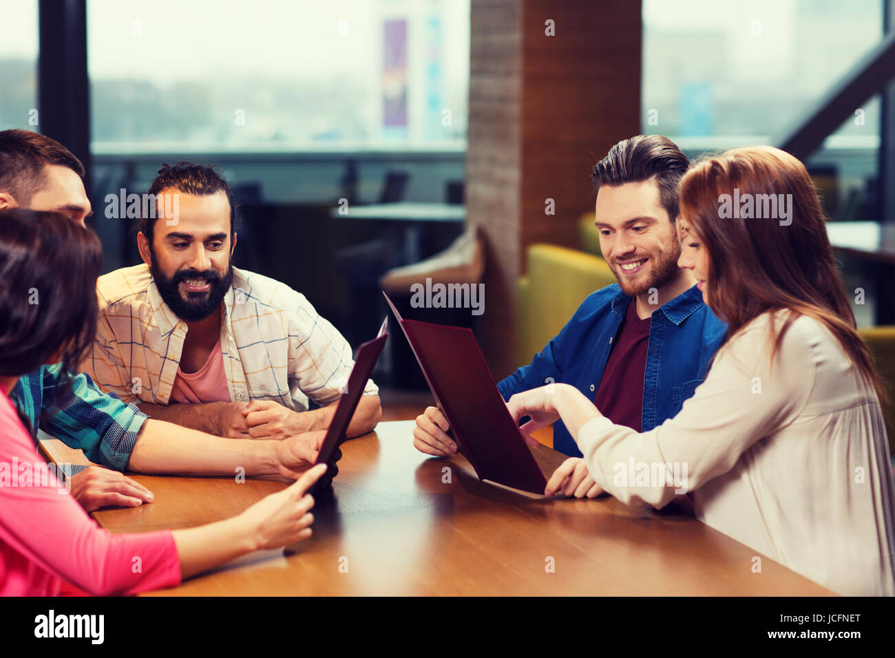 smiling friends discussing menu at restaurant Stock Photo - Alamy