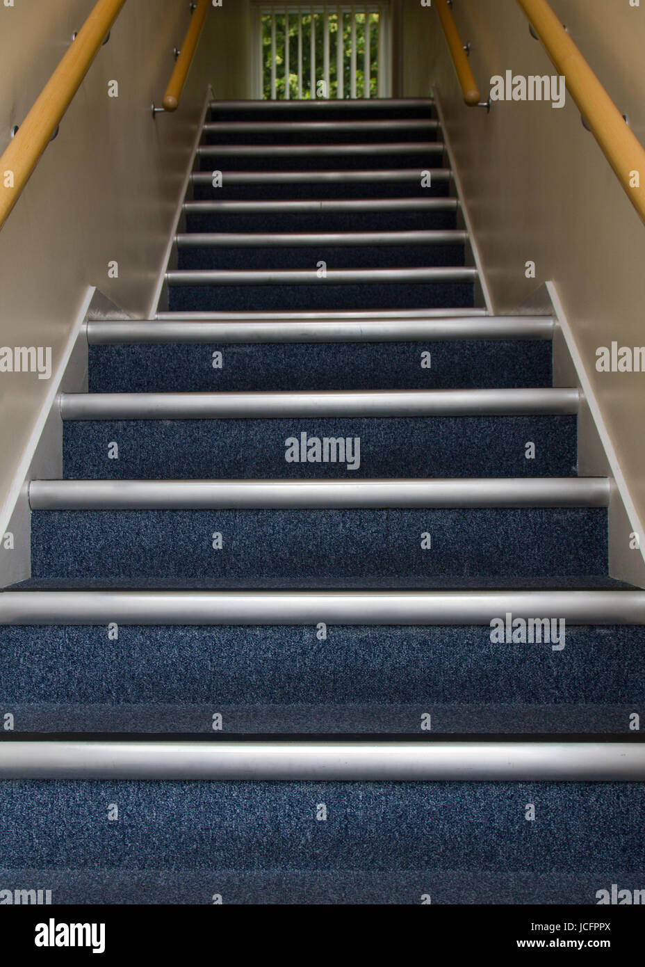 Stairway going up in office block with blue carpet, to the next floor with no obstacles or trip hazards. Landing halfway up the stairs Stock Photo