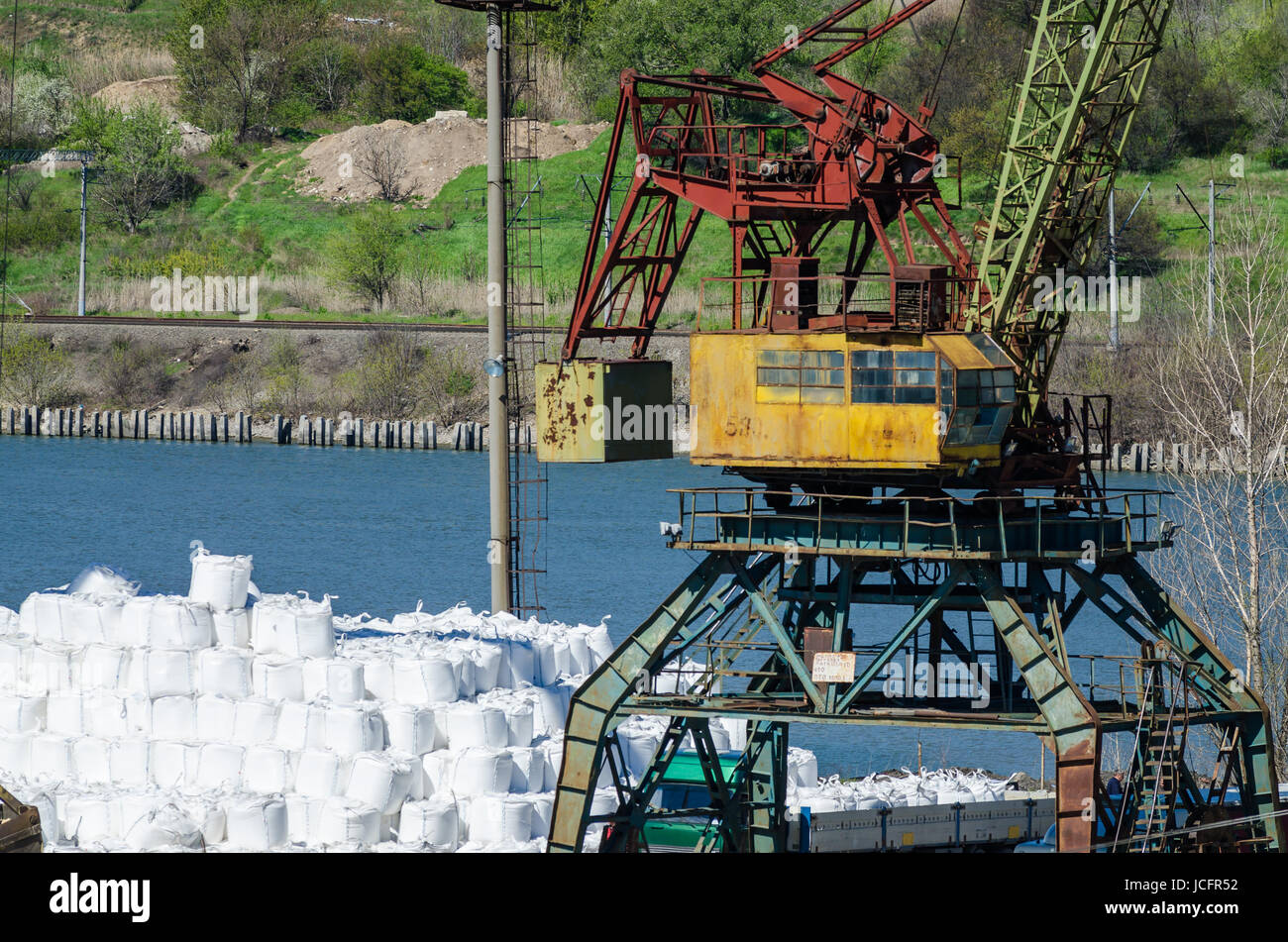 Crane in river port. Heavy cranes unloading metal to import. Steel delivery Stock Photo