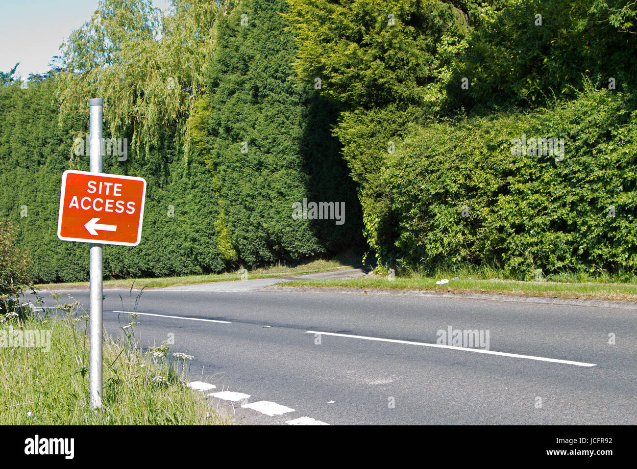 B-Road in county side with conifer edge and red site sign. Tarmac/Asphalt surface with white  broken lines Stock Photo