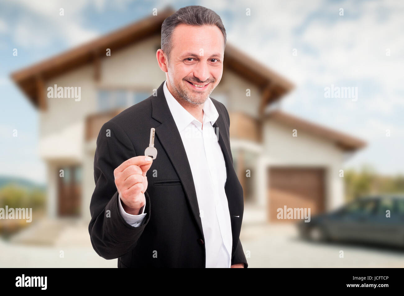 Young realtor offering house keys as real estate selling concept Stock Photo