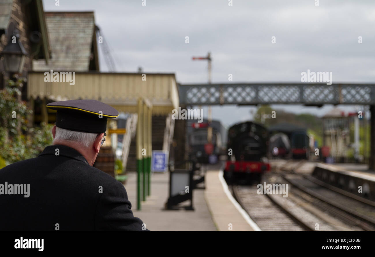 Embsay and Bolton Abbey Railway Steam Engine Tourist Heritage Railway Train Arrives Soft Focus with Volunteer Station Master Sharp Focus in foreground Stock Photo