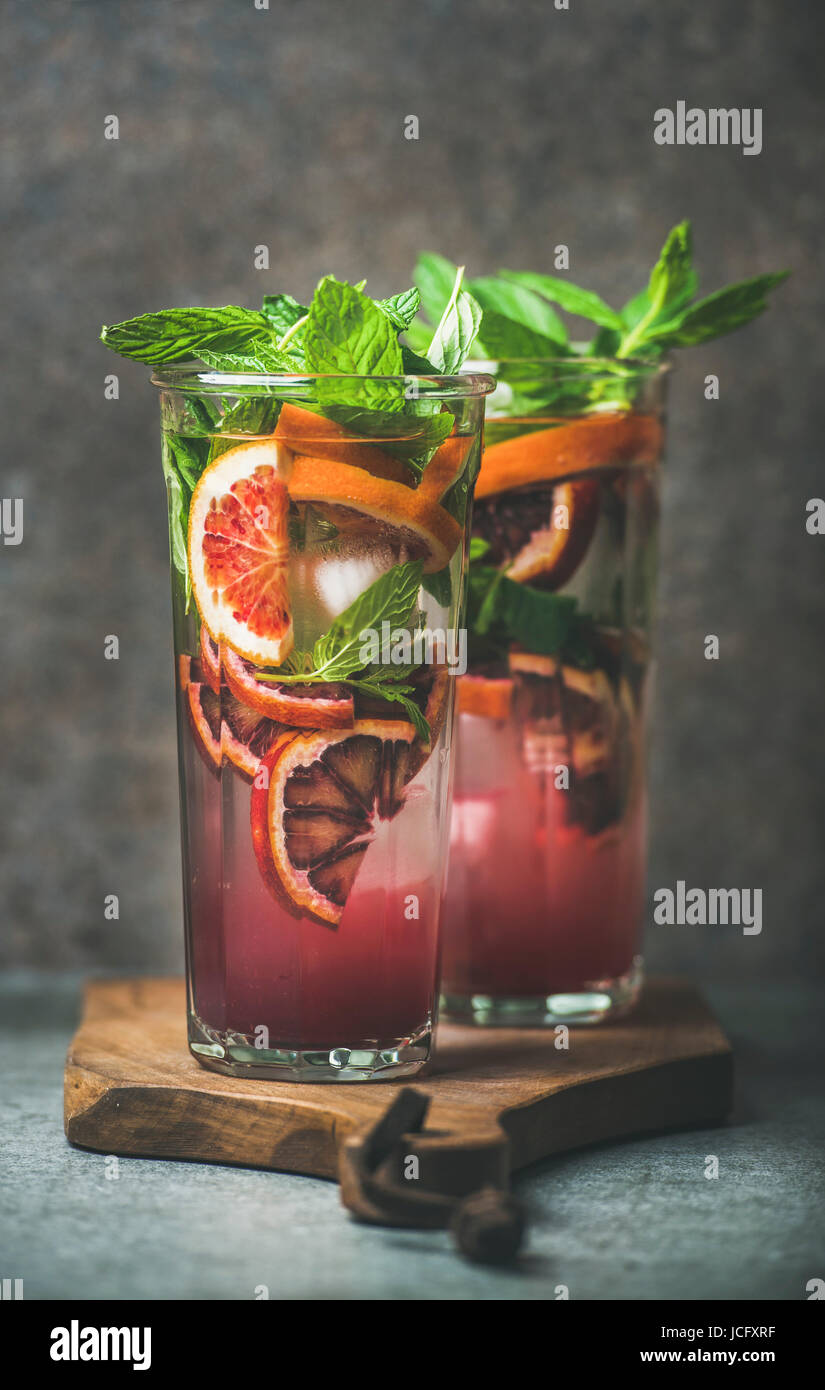 Blood orange citrus lemonade with mint and ice in tall glasses, dark ...