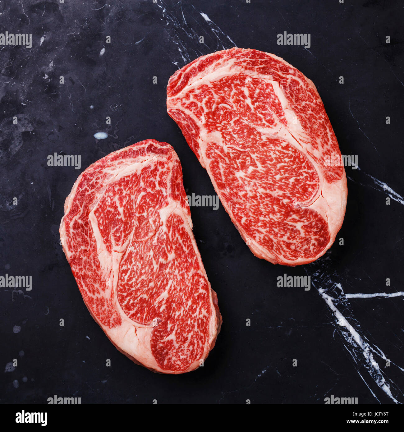 Raw fresh marbled meat Steak Ribeye Black Angus on black marble background Stock Photo