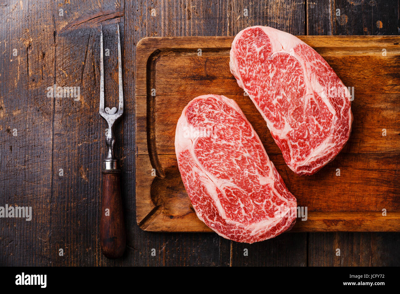 Raw fresh marbled meat Steak Ribeye Black Angus and meat fork on wooden background copy space Stock Photo