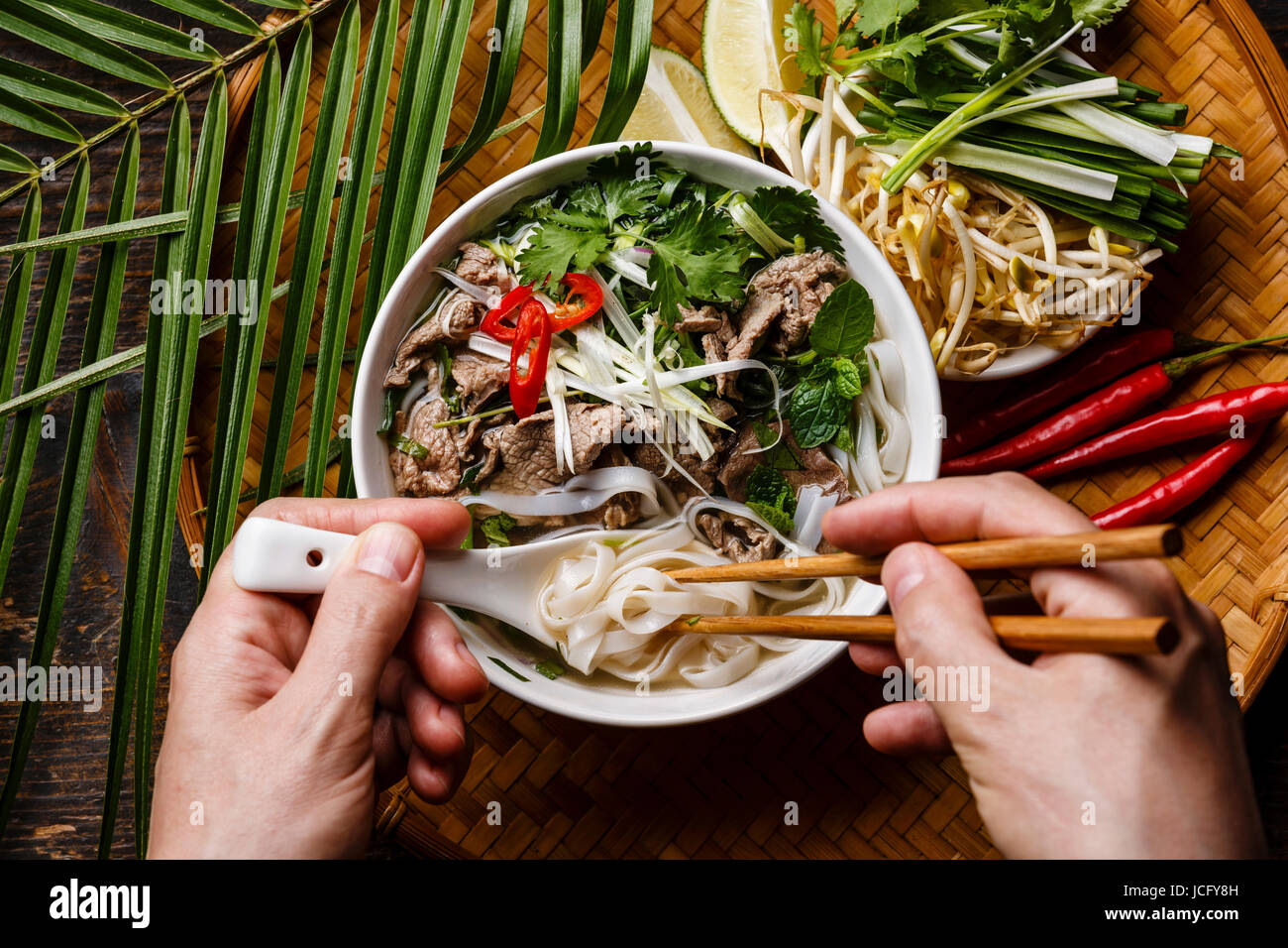 Pho Bo Soup with beef and chopsticks in male hands close-up Stock Photo