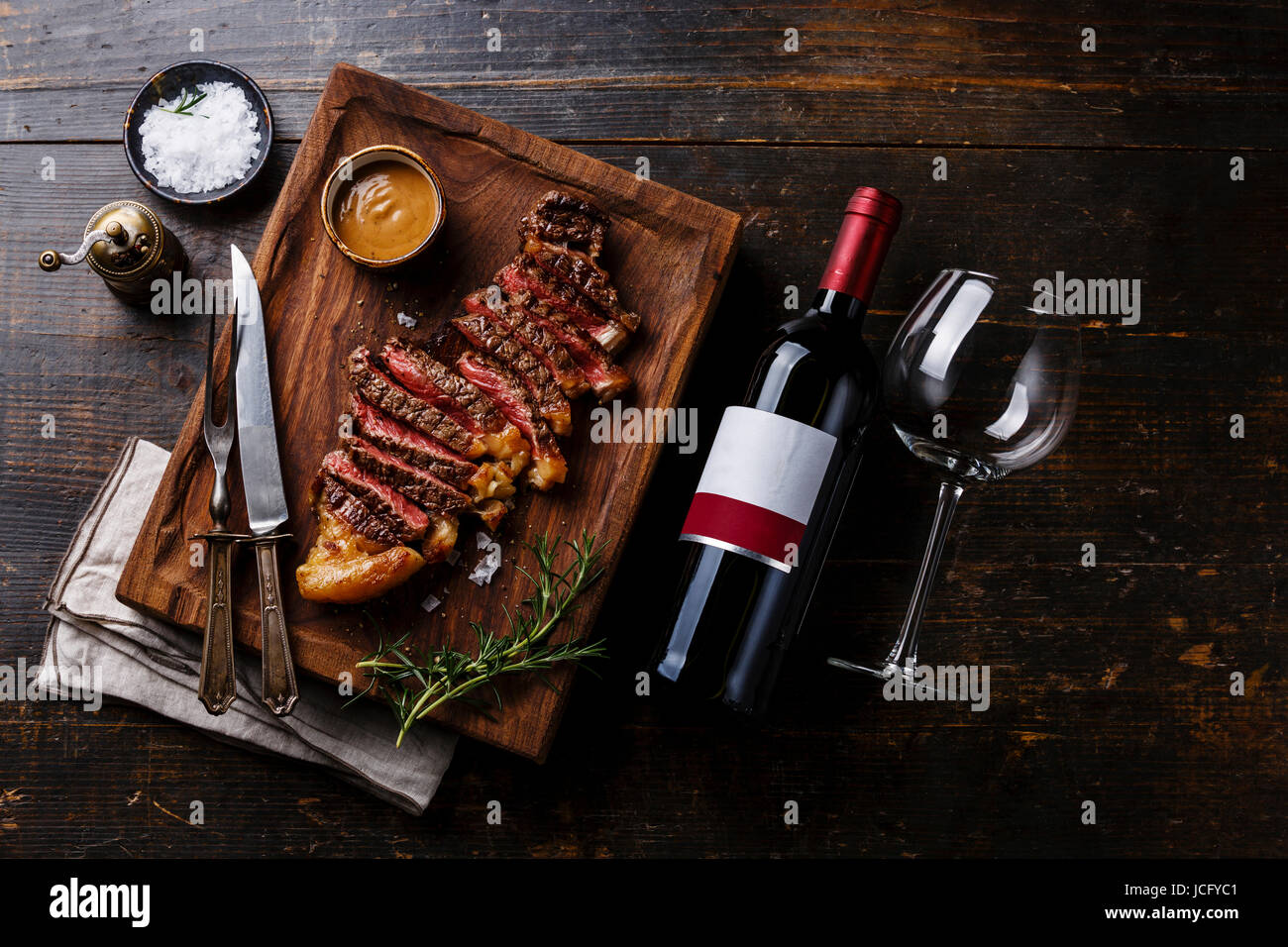 Grilled sliced Steak Striploin with Pepper sauce and bottle of Red wine ...