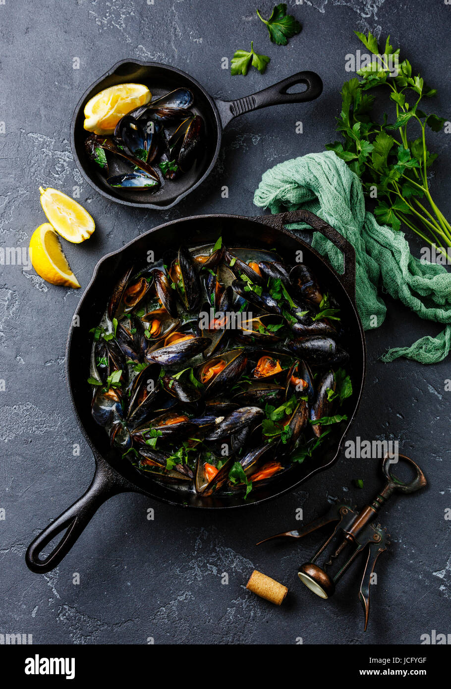 Mussels in black cooking pan with parsley on dark stone background Stock Photo