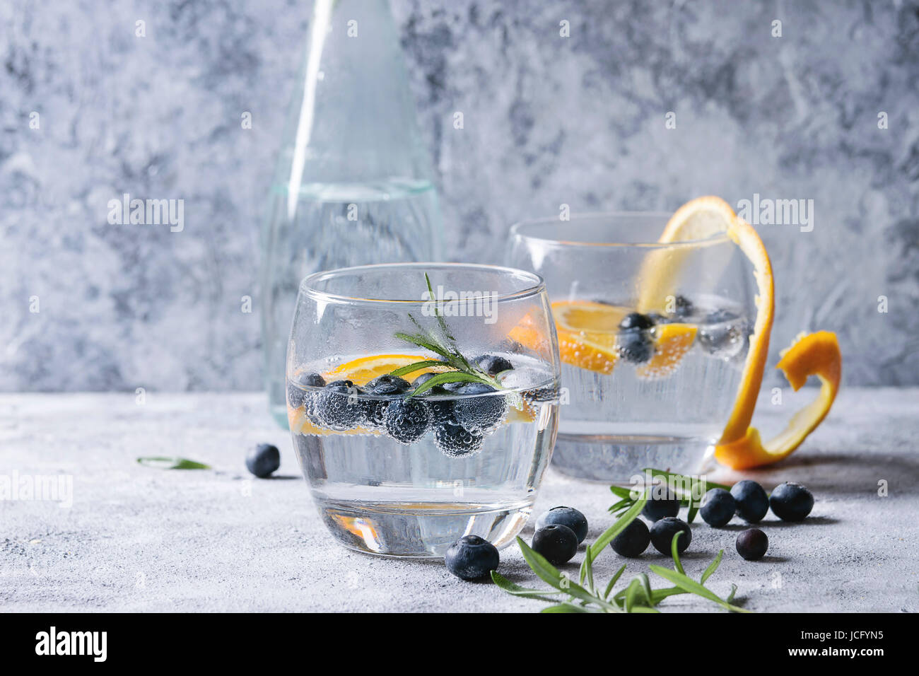 Tonic water cocktail with rosemary, blueberries and orange. Two cold