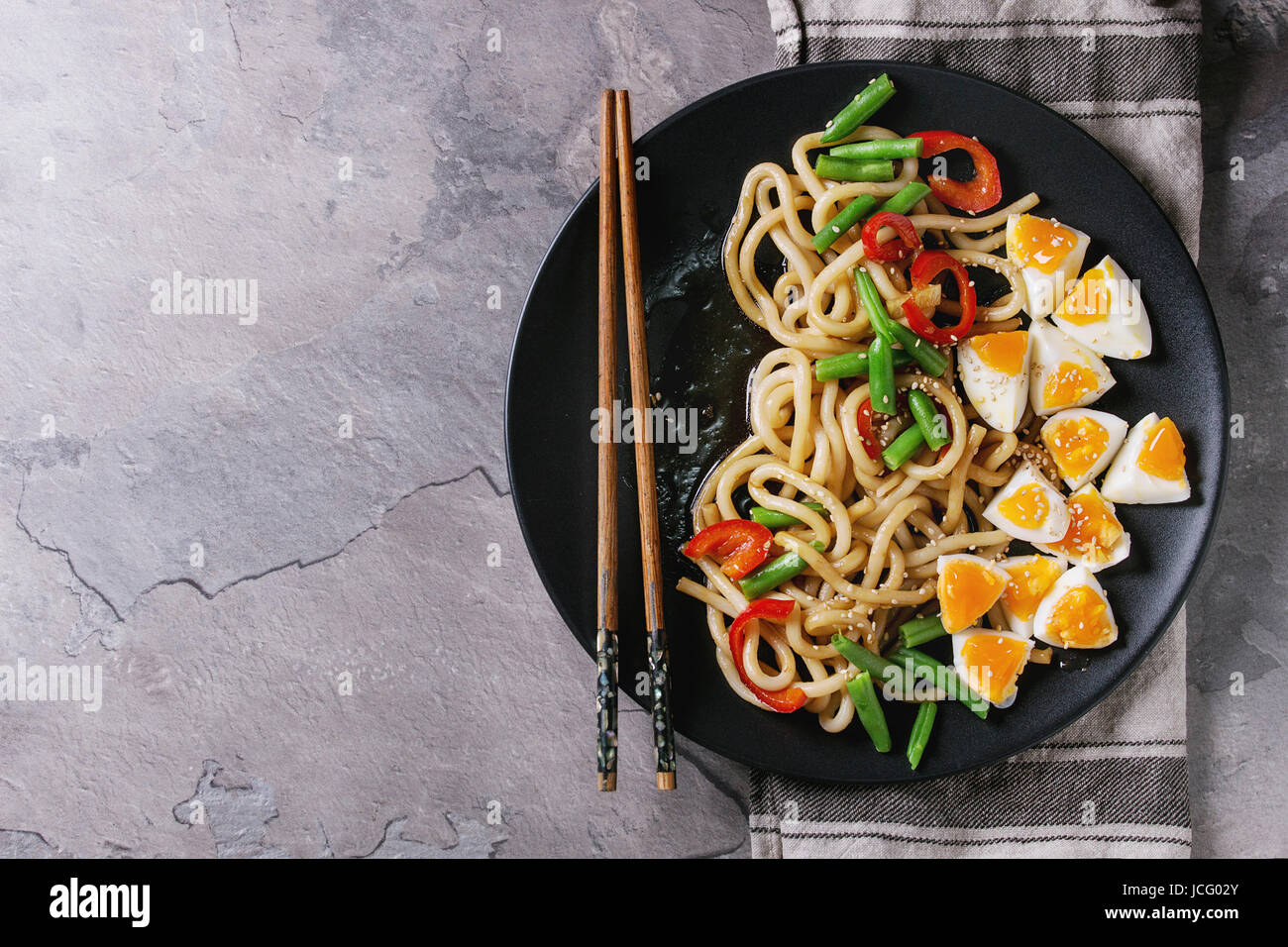 Cooking stir fry udon noodles, green beans, sliced paprika, boiled eggs