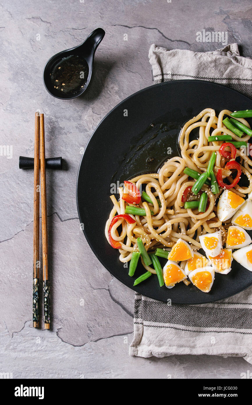 Cooking stir fry udon noodles, green beans, sliced paprika, boiled eggs