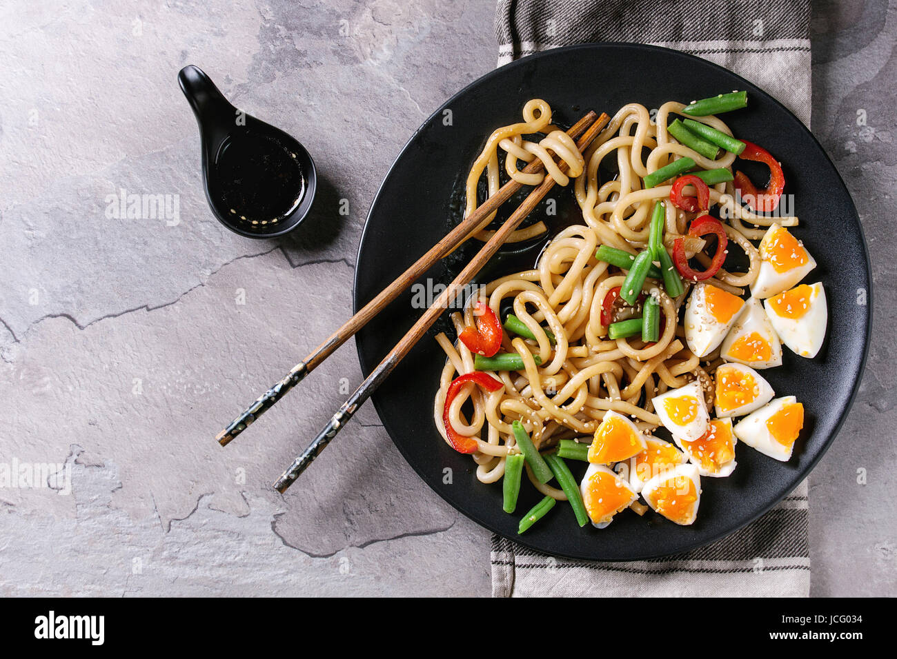 Cooking stir fry udon noodles, green beans, sliced paprika, boiled eggs