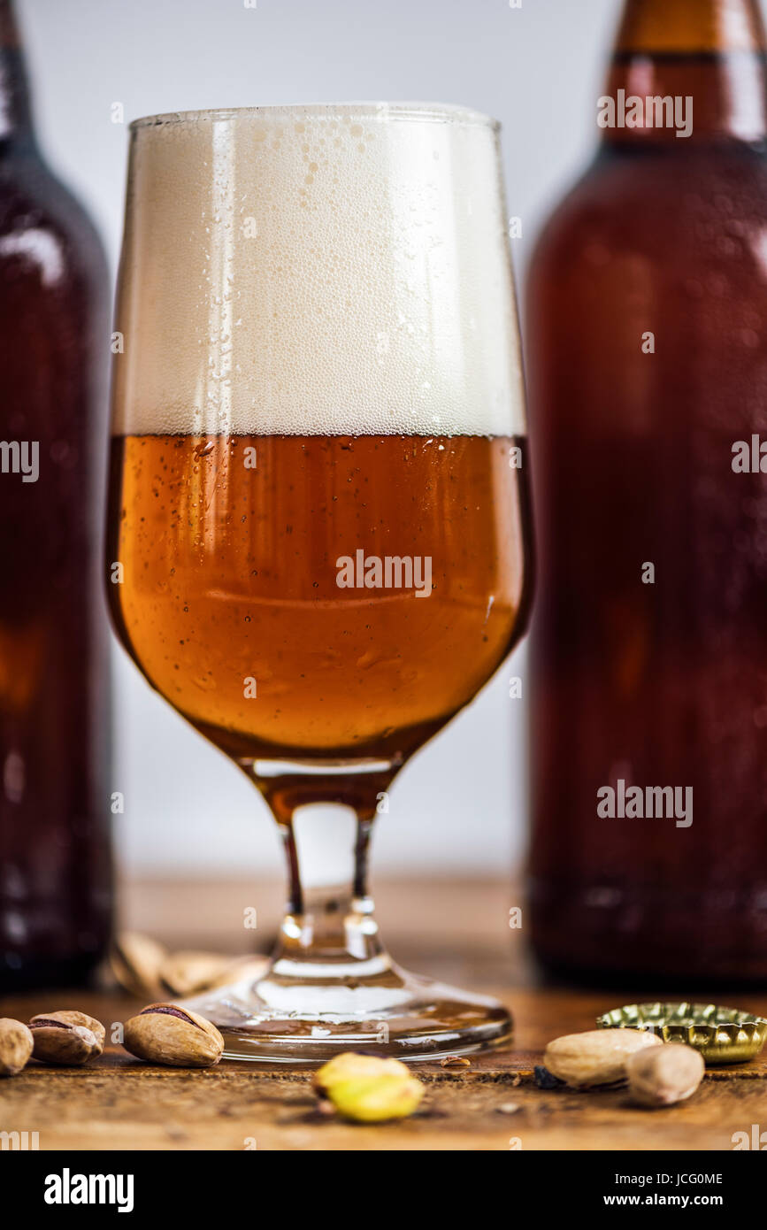 A glass of beer in front of beer bottles photographed from front view