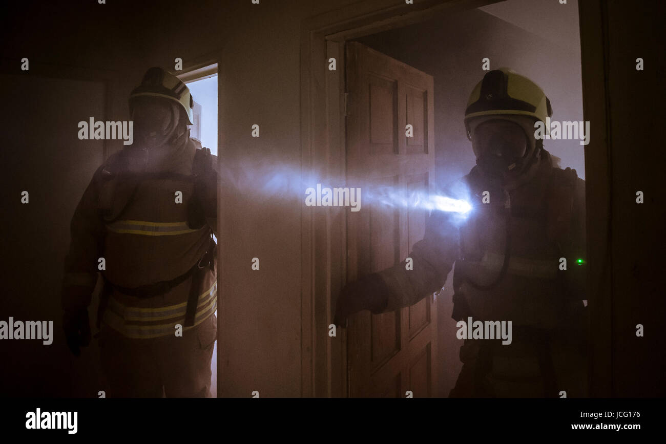 Firemen wearing breathing apparatus in a smoke filled room in a domestic house. Stock Photo
