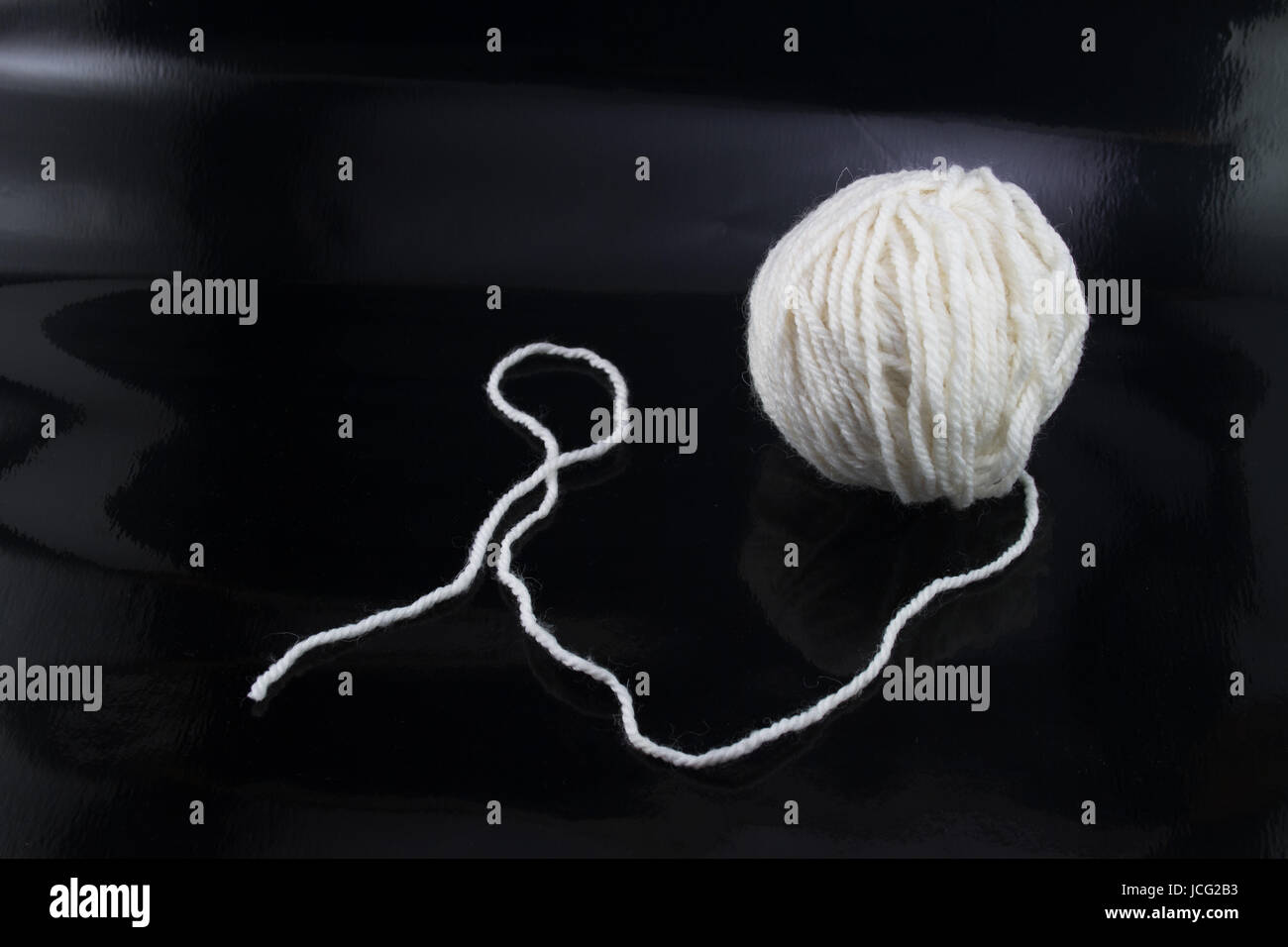 The white ball of wool thread on a black background, with the thread ...