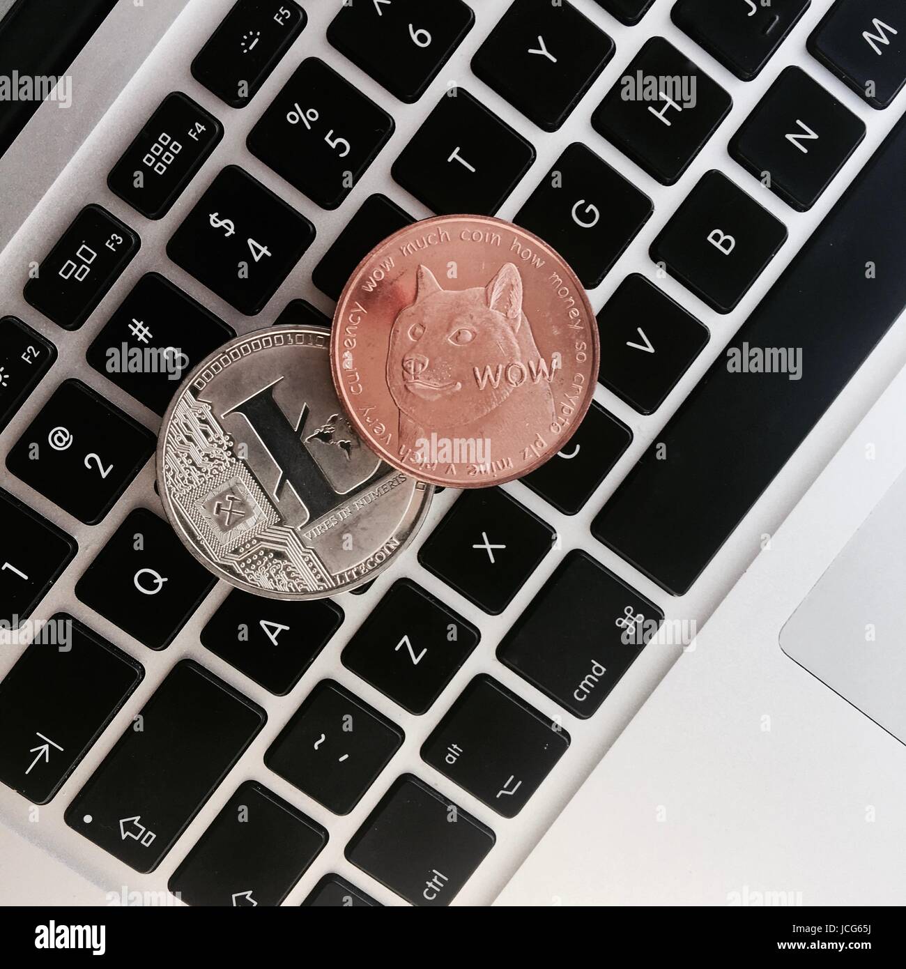 Cryptocurrency physical silver Litecoin coin and brass Dogecoin money on  the black computer keyboard Stock Photo - Alamy