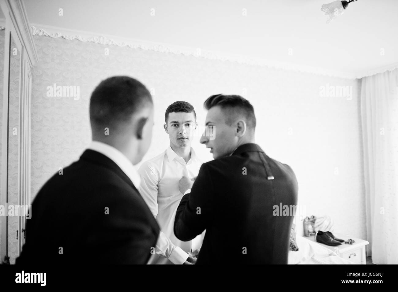 Groomsmen Helping Groom To Dress Up And Get Ready For His Wedding In A
