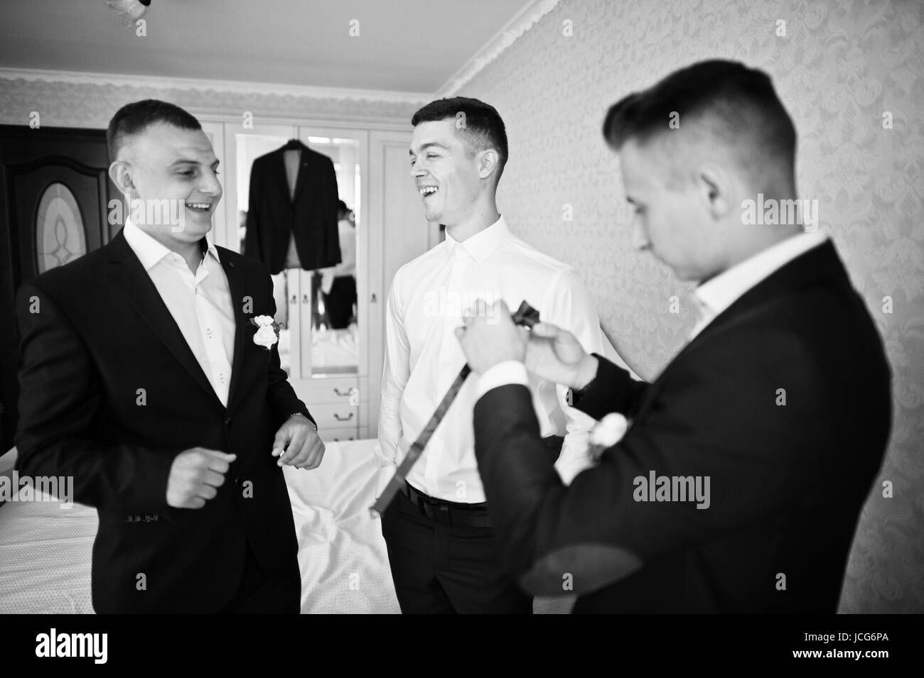 Groomsmen Helping Groom To Dress Up And Get Ready For His Wedding In A
