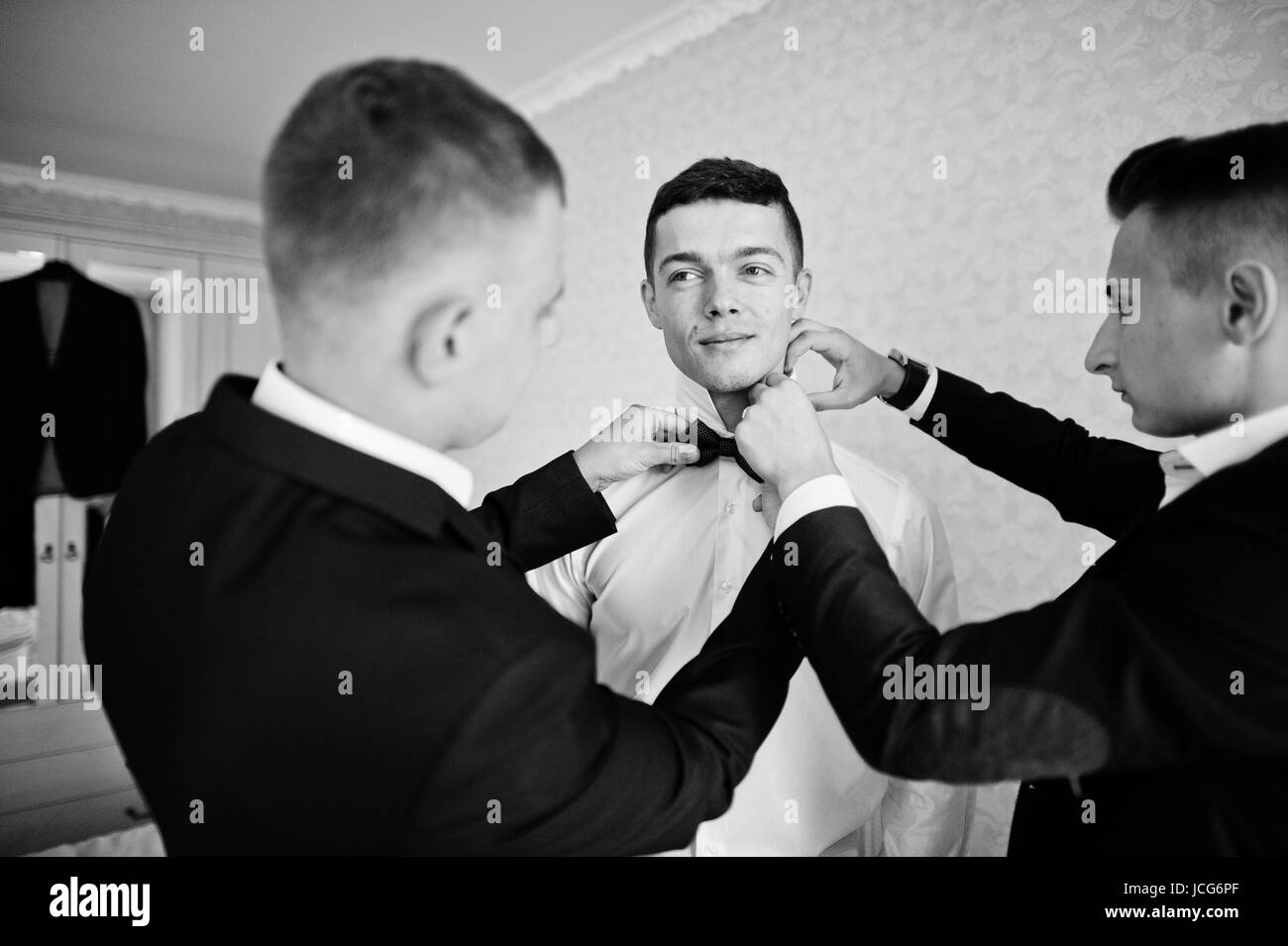 Groomsmen Helping Groom To Dress Up And Get Ready For His Wedding In A