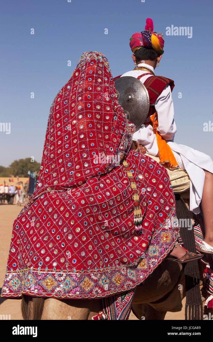 Indian boy and girl dressed in traditional clothing riding a camel as