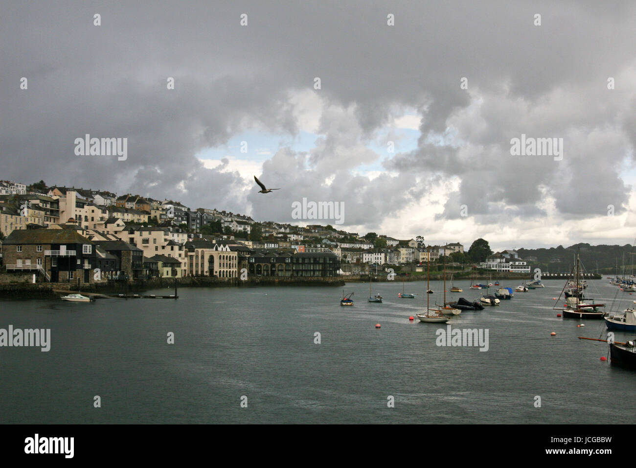 grey stormy clouds over Falmouth bay in Cornwall with boats moored and lone bird in flight Stock Photo