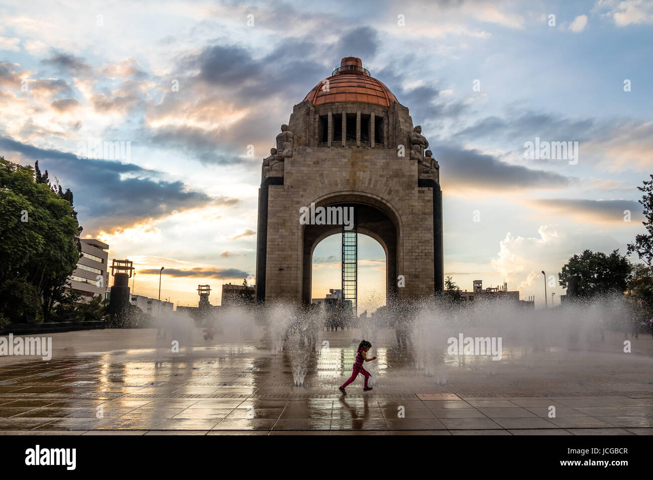 Girl playing with the water fountain in front of Monument to the Mexican Revolution (Monumento a la Revolucion) - Mexico City, Mexico Stock Photo