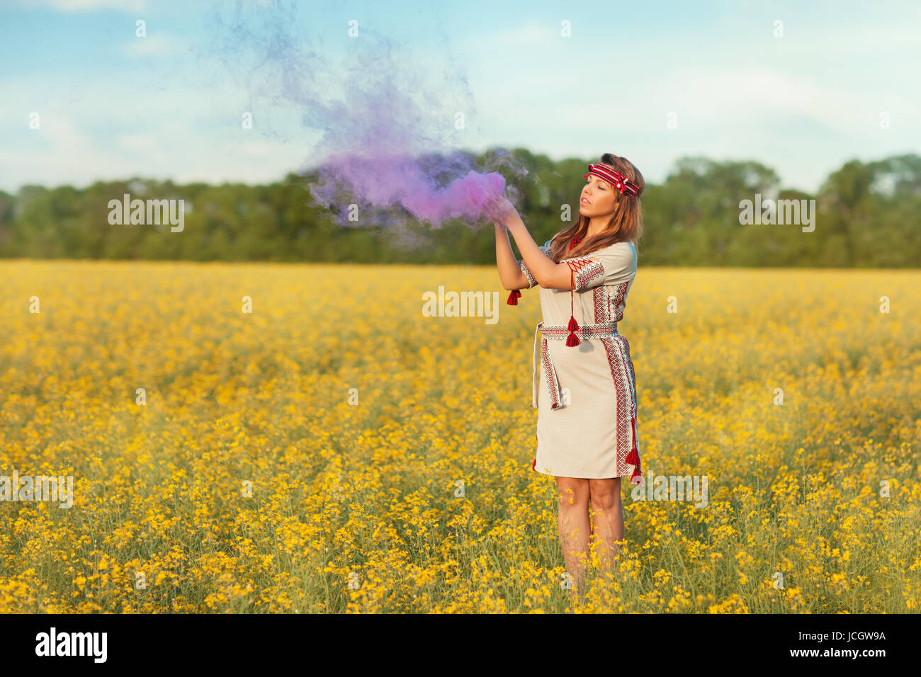 A girl stands in a field of yellow flowers, she raised her hands to the