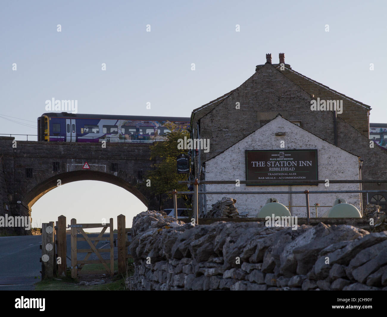 Arriva Rail North service 2H96 the 1806 from Leeds to Carlisle on Tuesday 9th May 2017 about to cross Ribblehead Viaduct passing the Station Inn pub. Stock Photo