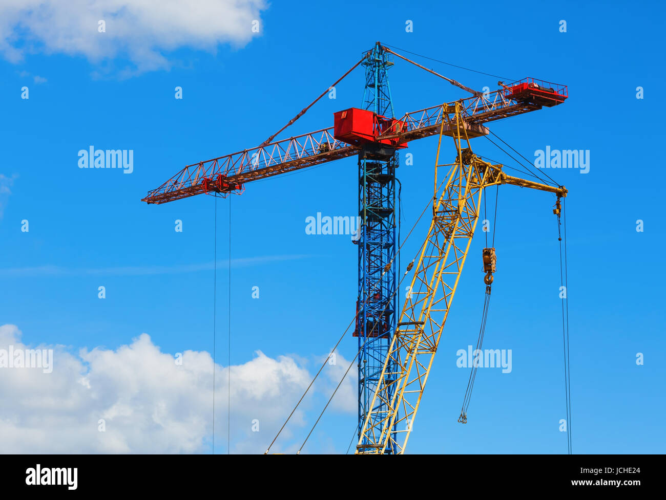 Two tower cranes against blue sky background Stock Photo - Alamy