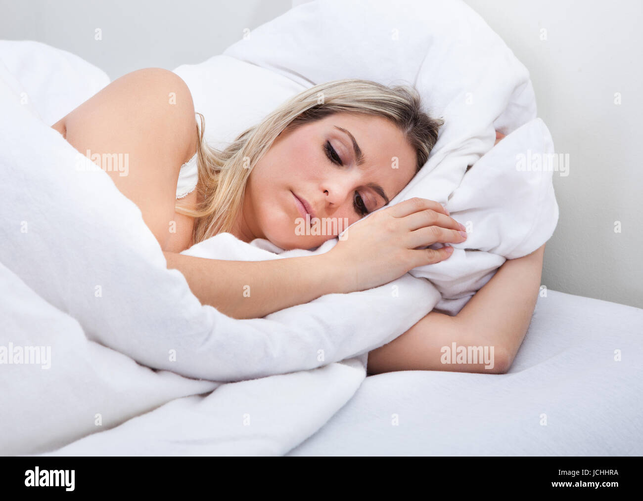 Close-up of upset woman lying on bed Stock Photo