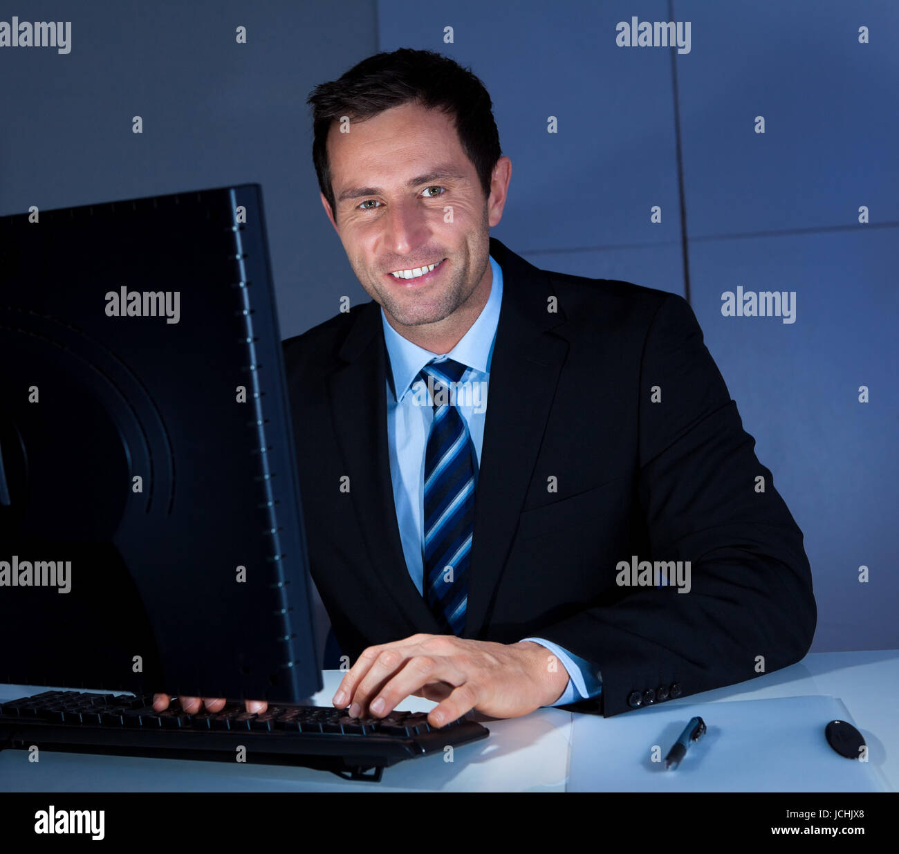 Portrait Of Happy Businessman Using Computer At Workplace Stock Photo ...