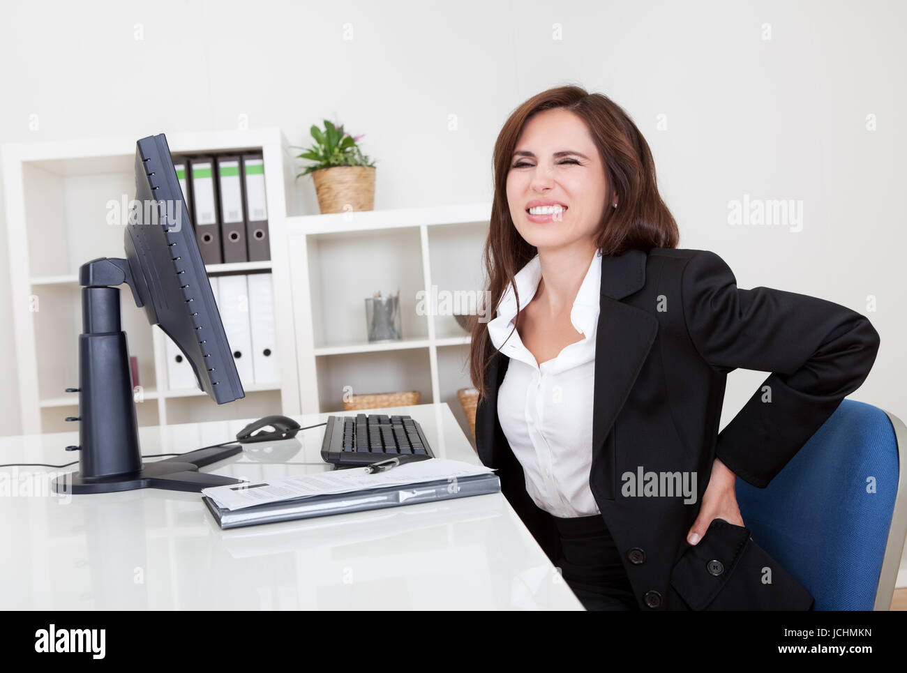 Young businesswoman having back pain while sitting at office desk Stock ...