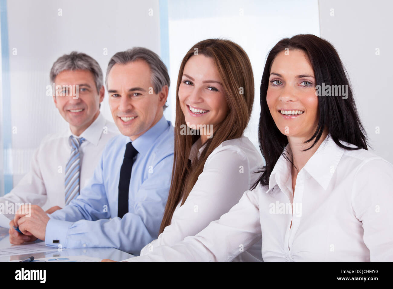 Portrait Of Happy Businesspeople Sitting In A Row Stock Photo - Alamy