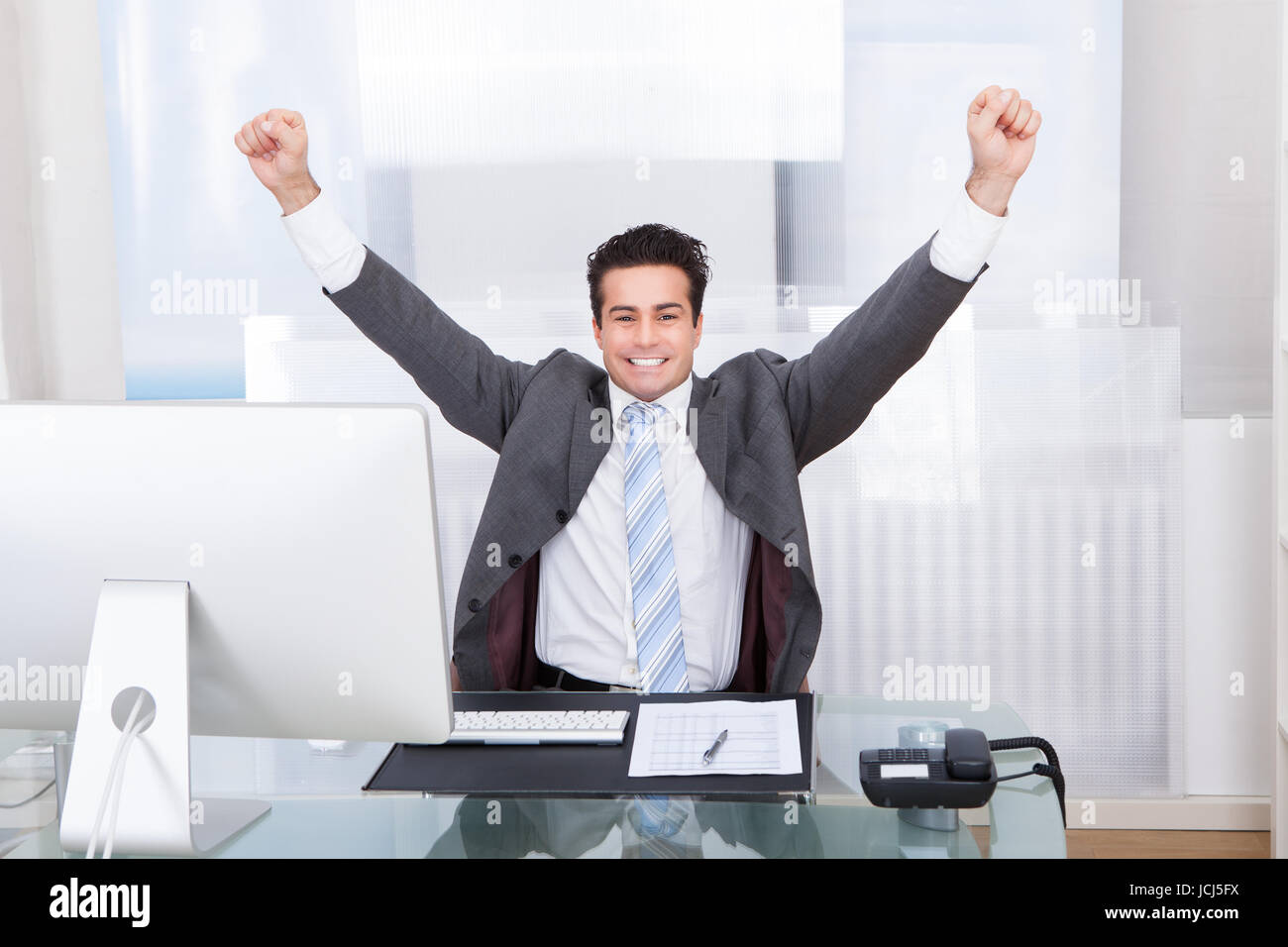 Excited Young Businessman Raising His Hands In Joy Stock Photo - Alamy