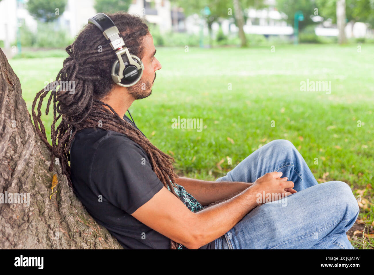 Man sitting in park with ear-phone,Bonn,Germany Stock Photo