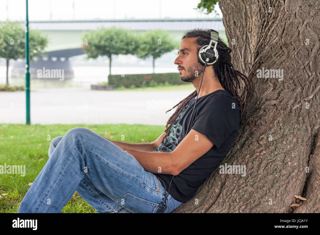 Man sitting in park with ear-phone,Bonn,Germany Stock Photo