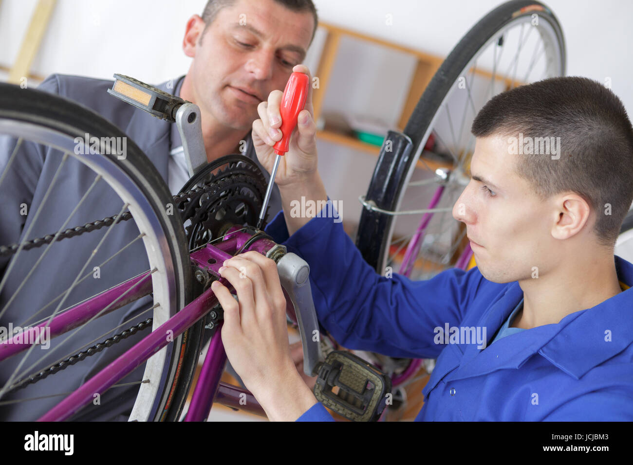 bicycle mechanic and apprentice repairing a bike in Stock