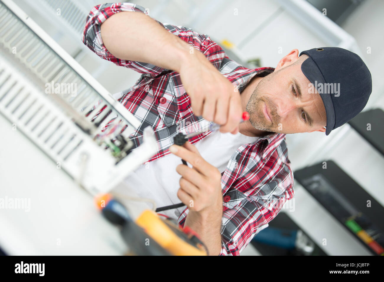 technician installing digital thermostat using screwdriver Stock Photo