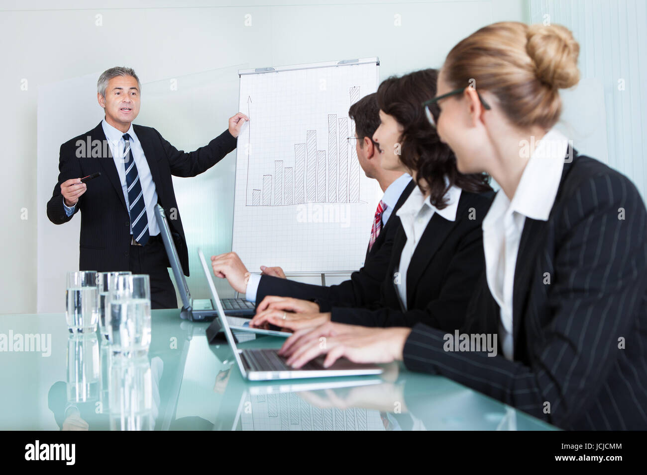 A senior business executive delivering a presentation to his colleagues ...