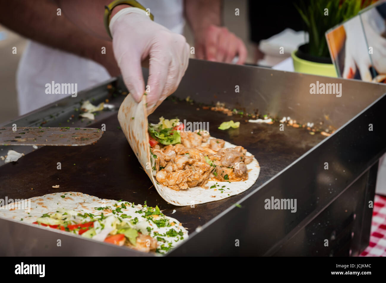 Hands of cook preparing fajita wrap with beef and vegetable salad. Mexican food. Party food. Stock Photo