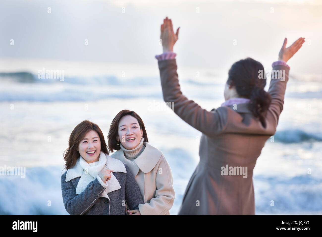 Three smiling middle aged women on beach Stock Photo