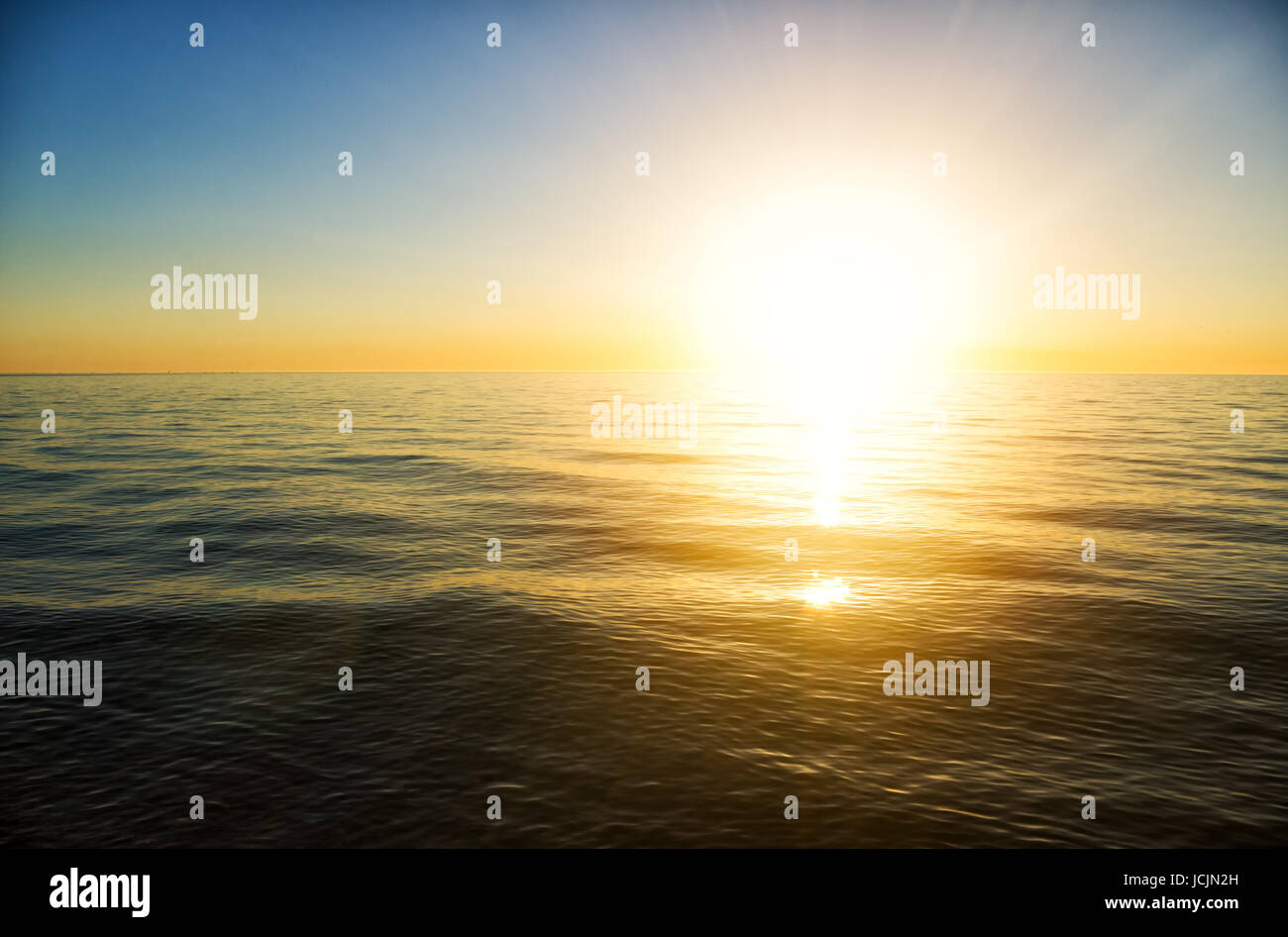 the sun to set over the horizon reflected in the sea Stock Photo