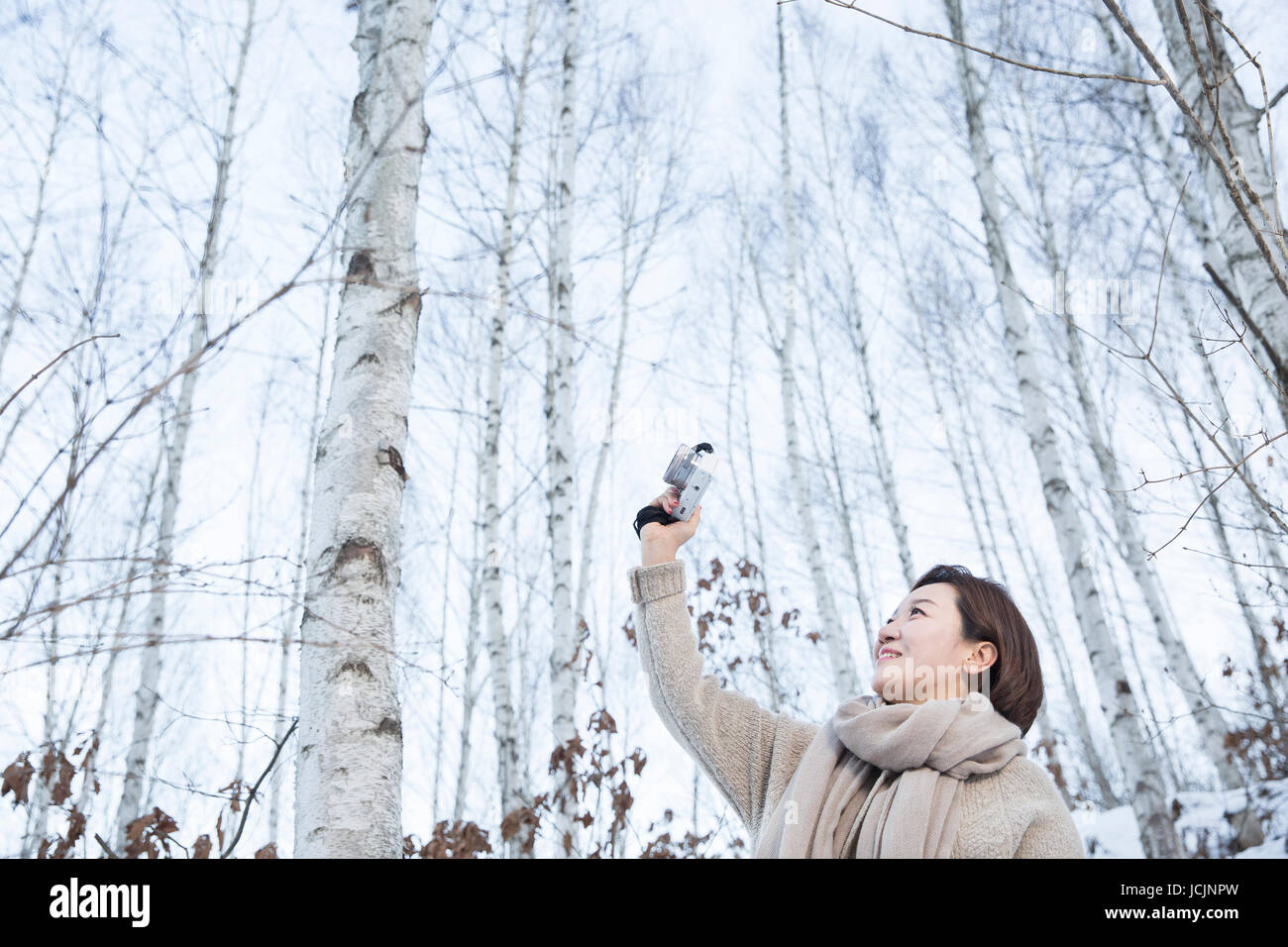 Portrait of smiling middle aged woman taking selfie in forest in winter ...