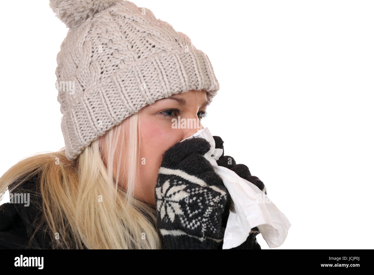 Junge Frau mit Taschentuch ist krank hat eine Erkältung oder Grippe, isoliert vor einem weissen Hintergrund Stock Photo