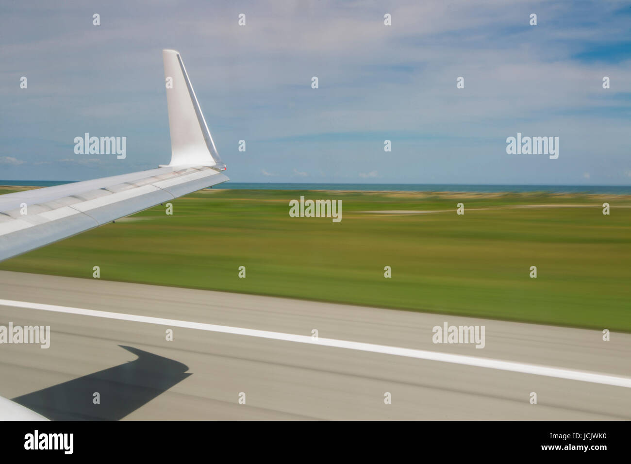 Slow shutter view from inside of plane taking off showing wing tip Stock Photo