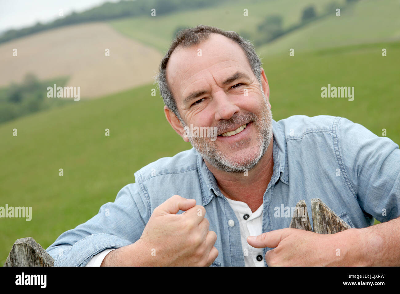 Portrait of smiling farmer leaning on fence Stock Photo - Alamy