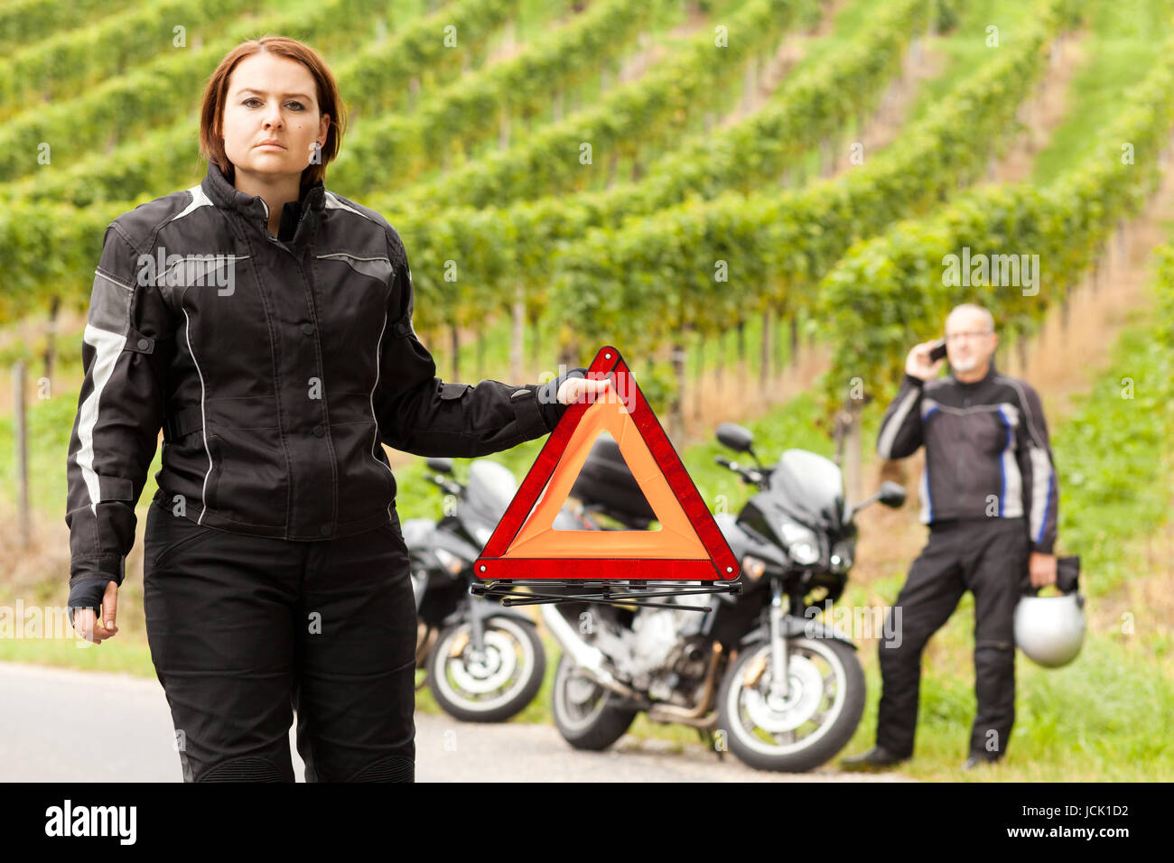Motorradfahrerin mit Pannendreieck bei einer Panne Stock Photo - Alamy