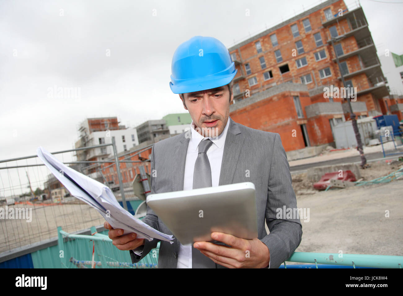 Architect checking plan of construction with tablet Stock Photo - Alamy