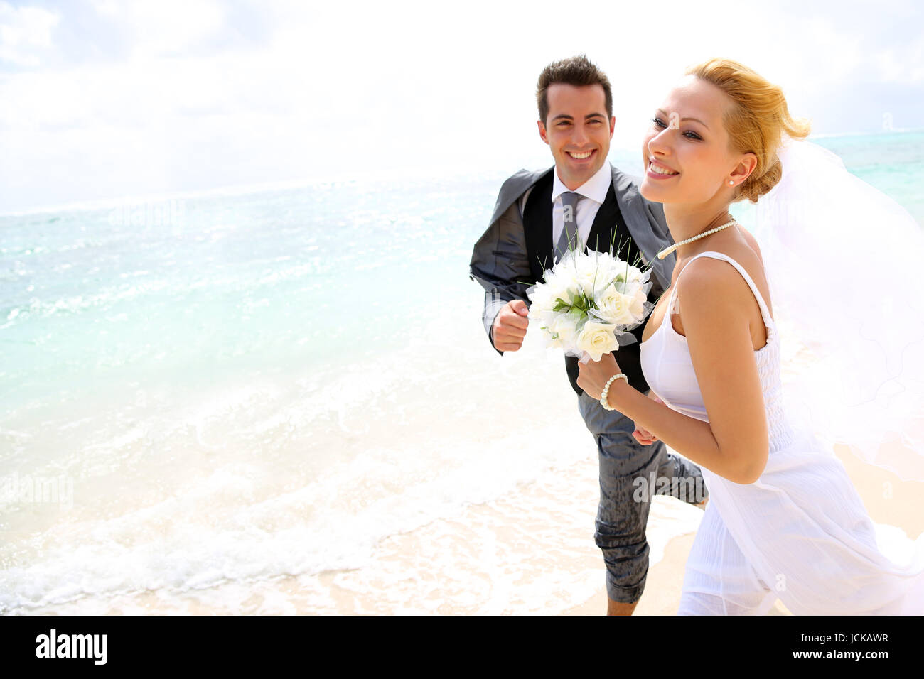 Just married couple running on a sandy beach Stock Photo - Alamy